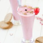 Two glasses of strawberry smoothie on a wooden table, perfect for seniors looking for wellness tips and diet advice.