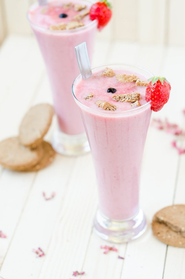 Two glasses of strawberry smoothie on a wooden table, perfect for seniors looking for wellness tips and diet advice.