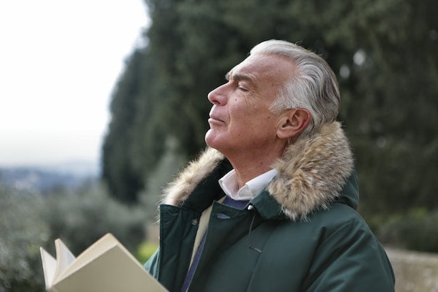 An older man reading a book in a park, seeking diet advice.