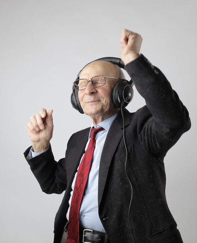 An elderly man in a suit and tie is listening to music while seeking wellness tips.