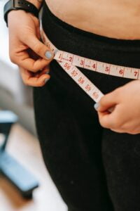 A woman is measuring her waist as she follows longevity tips for senior health.