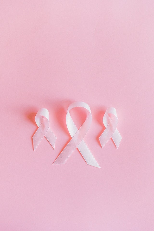 Three pink ribbons on a pink background that symbolize breast cancer awareness and promote wellness.