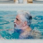 A man in a swimming pool, showcasing his wellness and longevity tips lifestyle while maintaining a white beard.