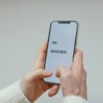 A woman holding a smartphone with the word ok boozer on it, offering anti-aging tips for senior health.