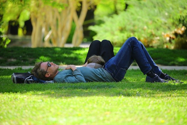 A man and woman enjoying the benefits of longevity as they lay on the grass in a park.