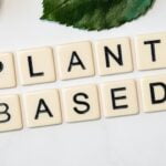 A visually appealing arrangement of the word "plant-based" carefully spelled out on a sleek marble table, highlighting the essence of healthy aging and anti-aging tips.