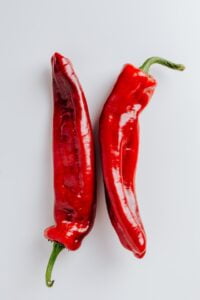 Two red chili peppers on a white background showcasing their vibrant color and fiery nature.