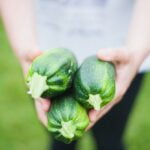 A person is holding a bunch of zucchini in her hands, offering diet advice for anti-aging and longevity tips.