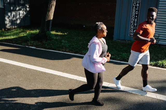A man and woman jogging on a street implementing longevity tips.