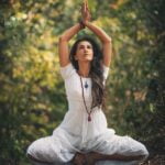 A woman is practicing yoga in the woods for senior health and aging tips.