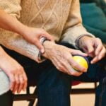 A man is holding a ball while an older man sits in a chair, providing diet advice for anti-aging.