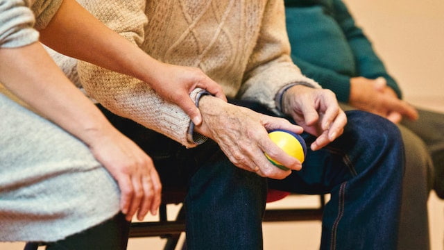 A man is holding a ball while an older man sits in a chair, providing diet advice for anti-aging.