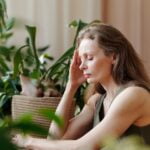 A woman is sitting at a table with plants in front of her, offering diet advice for senior health.