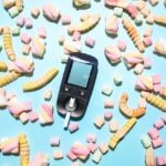 A mobile phone surrounded by candy and marshmallows on a blue background, showcasing longevity tips.