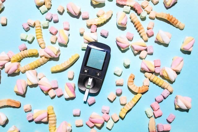 A mobile phone surrounded by candy and marshmallows on a blue background, showcasing longevity tips.