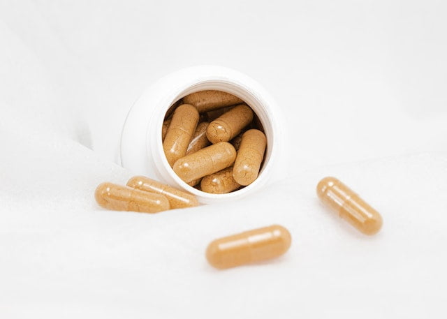 A white container with brown capsules sitting on top of a white surface, promoting longevity tips for senior health.