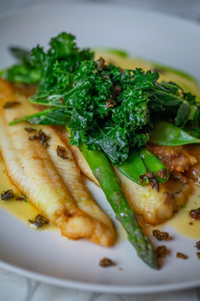 A plate with fish and greens on it, providing diet advice for senior health.