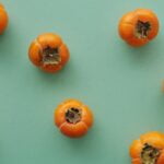 Persimmons on a green background, providing dietary wellness tips.