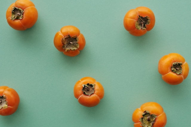 Persimmons on a green background, providing dietary wellness tips.