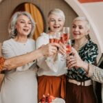 A group of older women toasting to a birthday cake while sharing longevity tips.