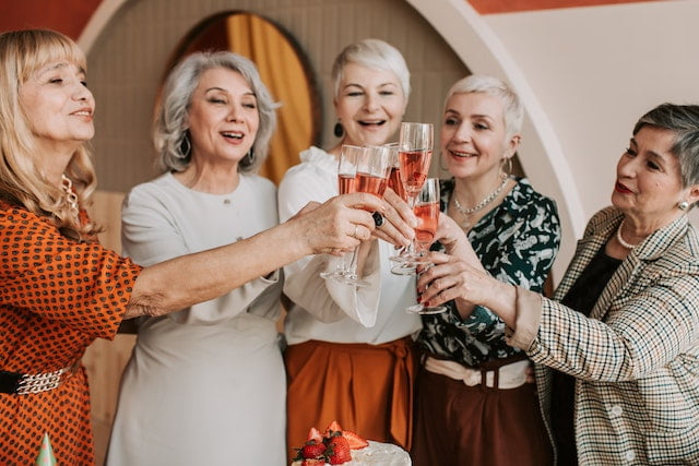 A group of older women toasting to a birthday cake while sharing longevity tips.