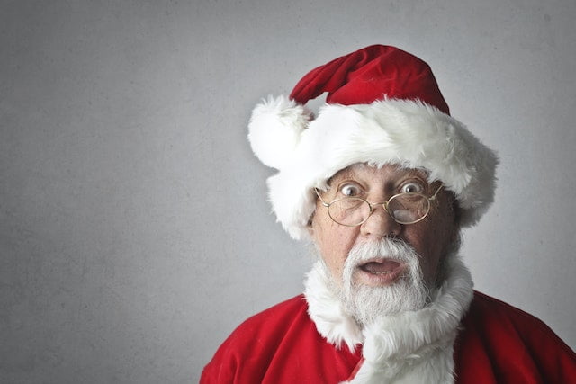 A man in a santa claus costume makes a surprised face while sharing wellness tips.