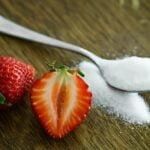 Strawberries and sugar on a wooden table, offering wellness tips for longevity and anti-aging.