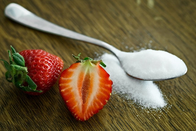 Strawberries and sugar on a wooden table, offering wellness tips for longevity and anti-aging.