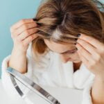 A woman is looking at her hair in front of a mirror while seeking senior health and wellness tips for longevity.