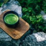 A cup of green tea, known for its wellness benefits, delicately placed on top of rocks.