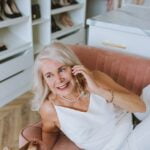 A woman sitting on a couch and talking on the phone, discussing senior health and wellness tips for longevity.