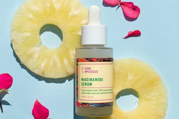 A bottle of pineapple oil surrounded by rose petals, providing rejuvenating anti-aging benefits.