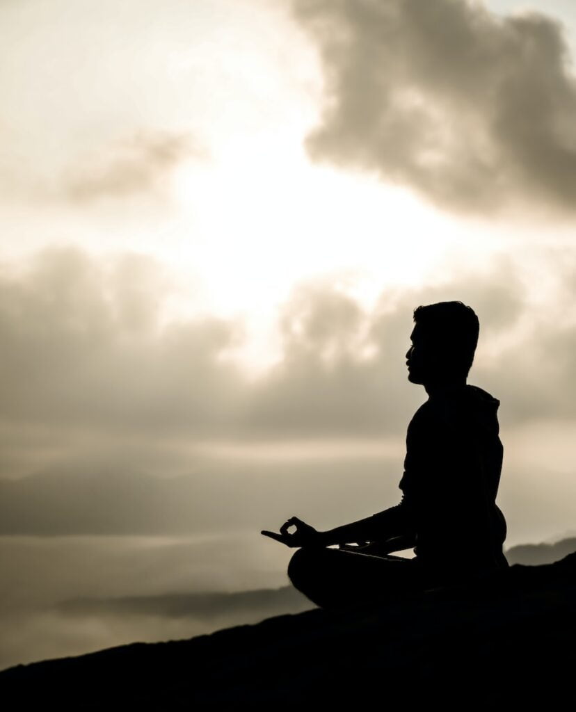a man sitting on top of a hill while meditating