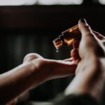 A woman's hand holding an essential oil bottle, offering longevity tips.