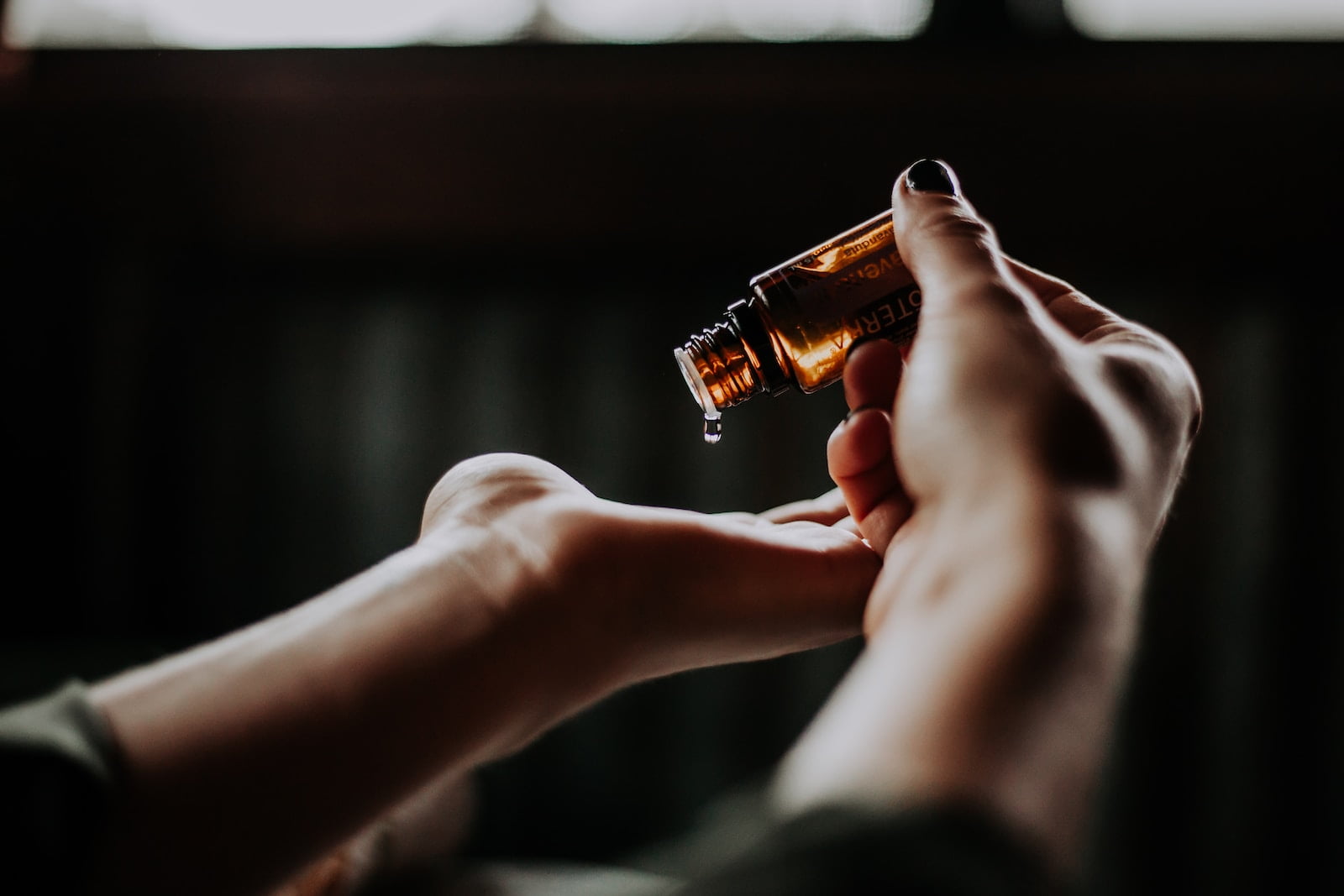 A woman's hand holding an essential oil bottle, offering longevity tips.