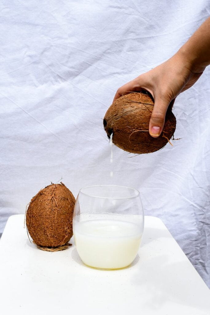 Person Pouring Drink from Coconut
