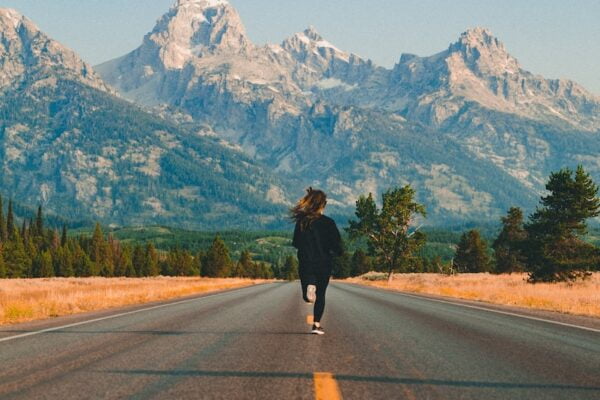 A woman walking down a road with mountains in the background, enjoying her wellness journey and embodying senior health.
