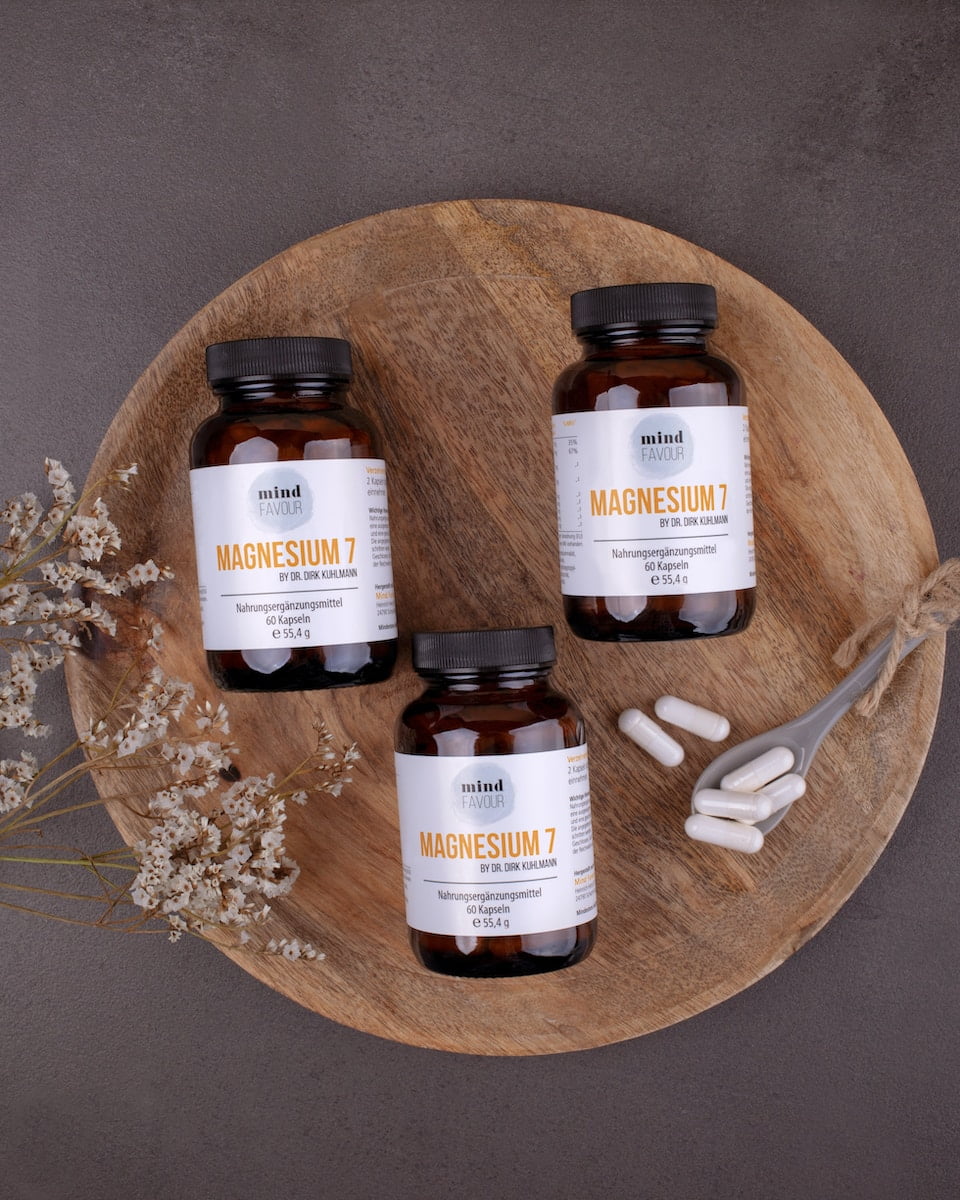 Three jars of supplements filled with wellness tips on a wooden plate.