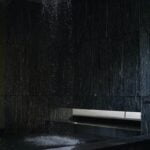 A rejuvenating shower in a dark room with a bench, offering wellness benefits and promoting healthy aging.