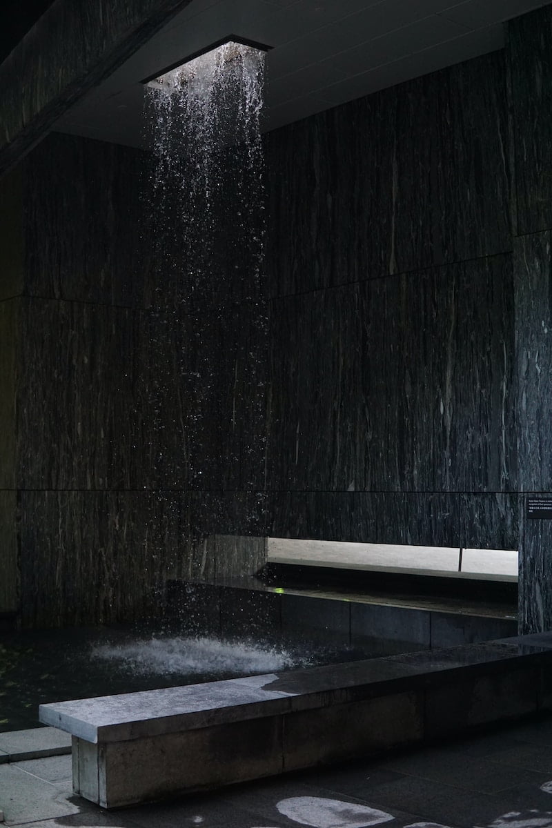 black wooden bench beside black concrete wall