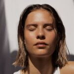 A woman with her eyes closed in a white top, portraying senior health and wellness tips.