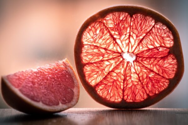 A grapefruit, known for its numerous health benefits and weight loss properties, is cut in half and sitting on a table.