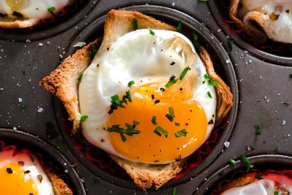 A muffin tin filled with eggs and herbs - a delicious and healthy option for senior health and wellness.