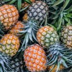 A pile of pineapples, known for their anti-aging and wellness properties, is arranged together in an appealing display.