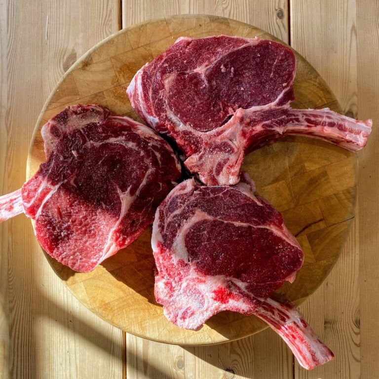 Three steaks, aged to perfection, are sitting on a wooden table.