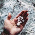 A person's hand holding a handful of salt, emphasizing diet advice.