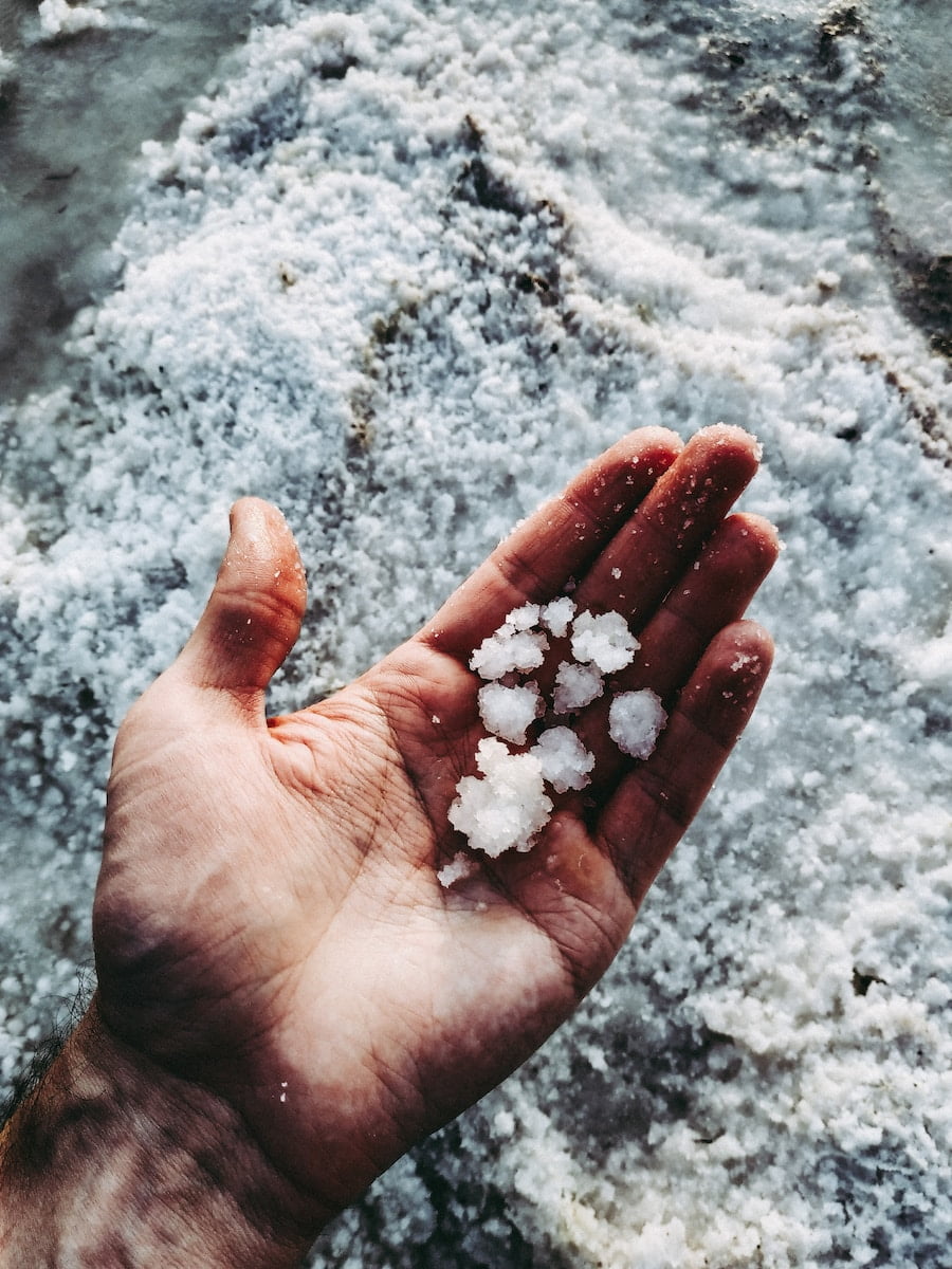 A person's hand holding a handful of salt, emphasizing diet advice.