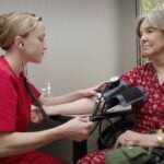 A nurse monitoring a woman's blood pressure for senior health.