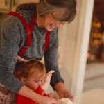 An older woman and a little girl making dough while exchanging aging tips.